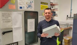 Wojciech Mrozik holding a battery pack in a lab.